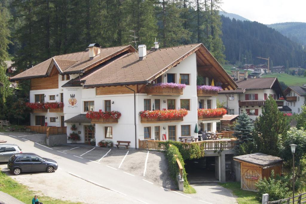 ein großes weißes Gebäude mit Blumen in den Fenstern in der Unterkunft Ferienwohnungen am Lärchenweg in Sexten