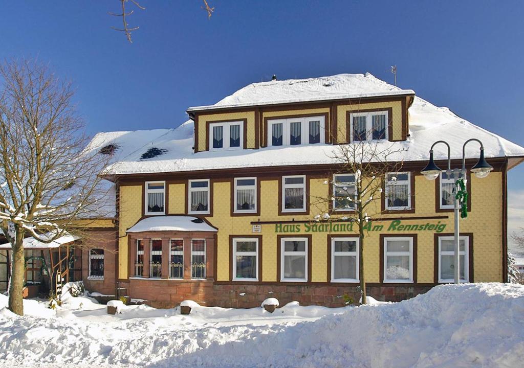 um grande edifício amarelo com neve em cima em Pension Haus Saarland em Oberhof