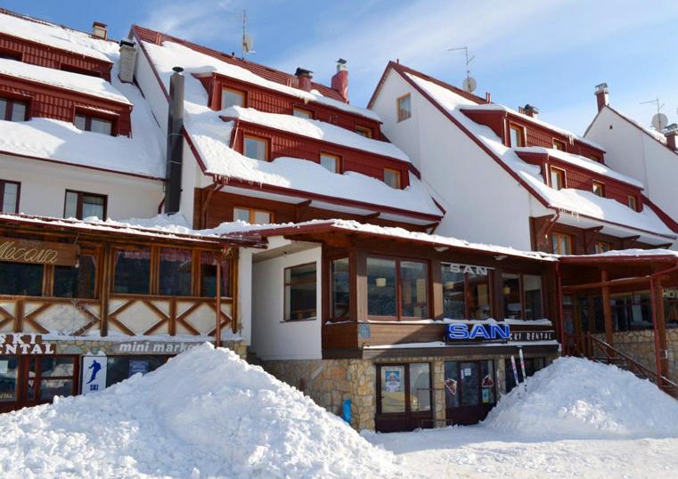 un edificio ricoperto di neve con un mucchio di neve di Hotel San a Jahorina