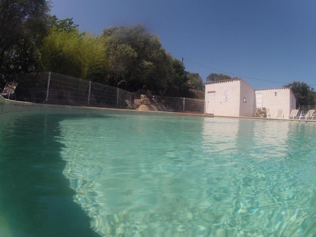 uma grande piscina de água azul clara em frente a um edifício em Residence La Beloutiere em Porto-Vecchio