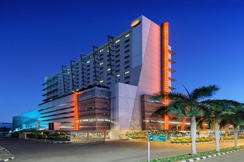 a tall building with palm trees in front of it at HARRIS Hotel and Conventions Kelapa Gading Jakarta in Jakarta