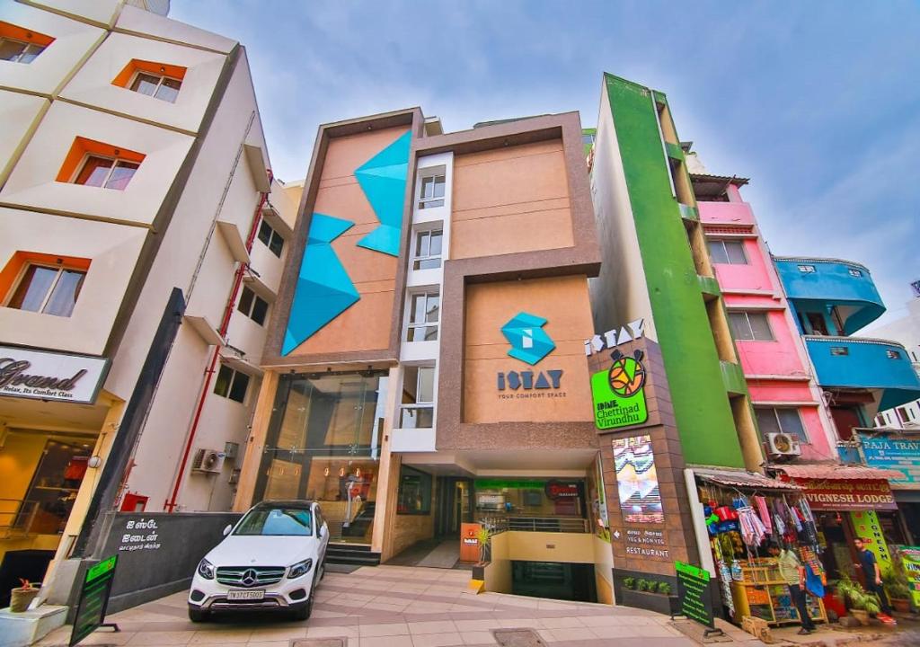 a car parked in a parking lot in front of buildings at Hotel iStay in Coimbatore