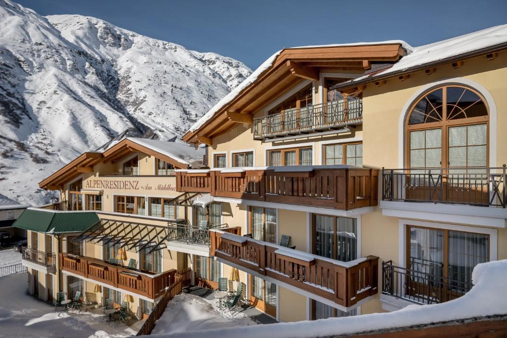 een hotel met sneeuw bedekte bergen op de achtergrond bij Alpenresidenz am Mühlbach in Obergurgl