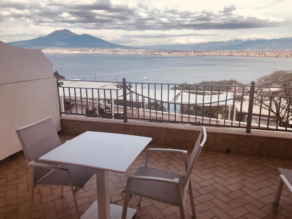 einen Tisch und Stühle auf einem Balkon mit Blick auf das Wasser in der Unterkunft Hotel Elisabetta in Castellammare di Stabia