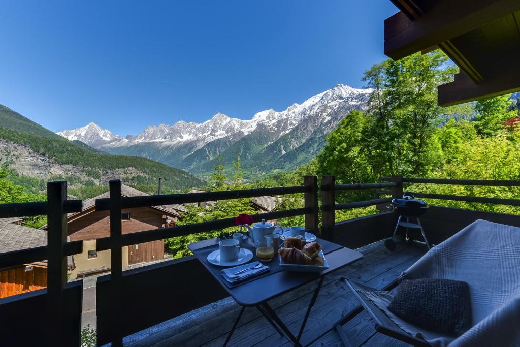 einen Tisch mit einem Teller Essen auf einem Balkon mit Bergblick in der Unterkunft Chalet Noemie in Les Houches