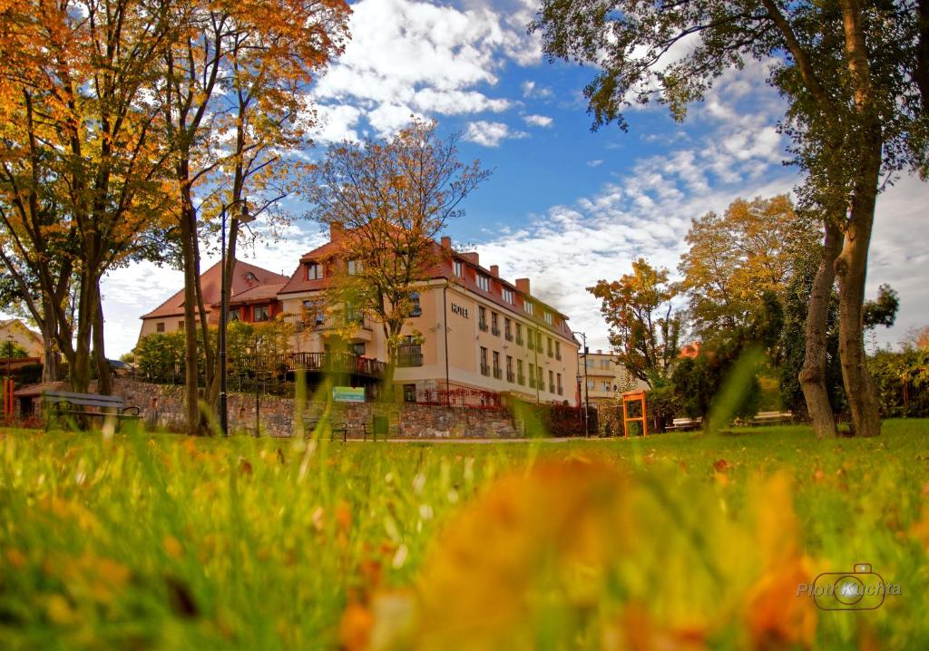 un grand bâtiment dans un champ planté d'arbres et d'herbe dans l'établissement Hotel i Restauracja "Pod Orłem", à Kartuzy