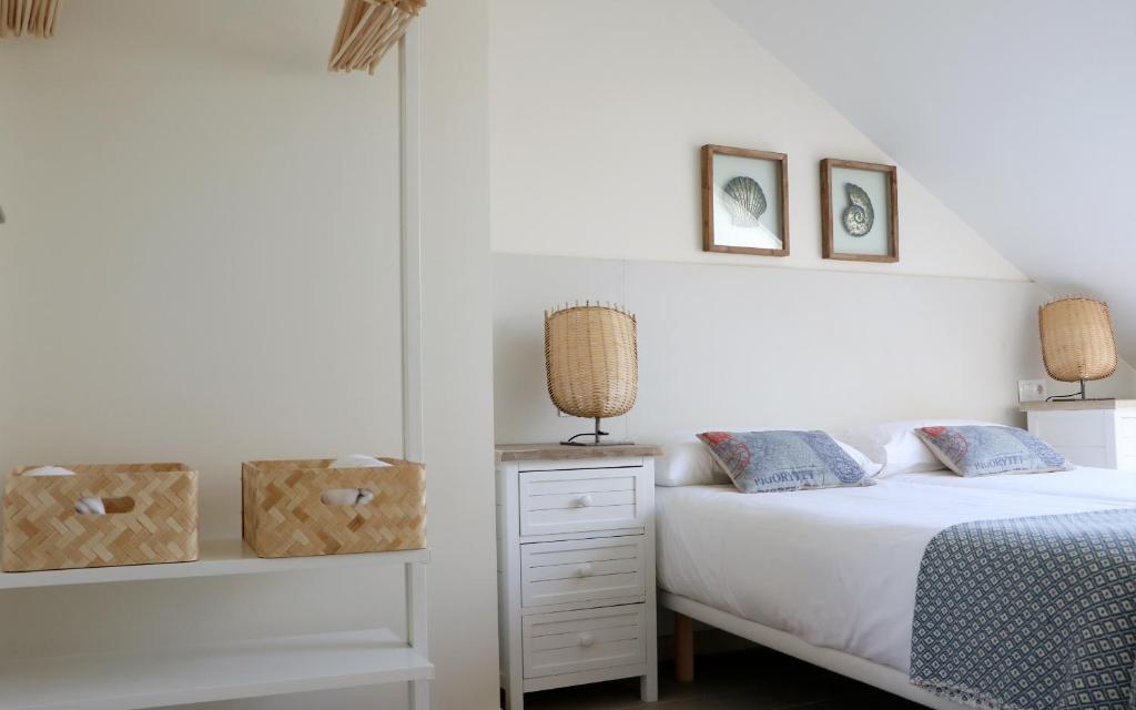 a white bedroom with a bed and a nightstand at Apartamentos Plaza Mayor in Gijón