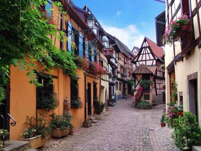 eine Kopfsteinpflasterstraße in einer Altstadt mit Gebäuden in der Unterkunft Auberge du Rempart in Eguisheim