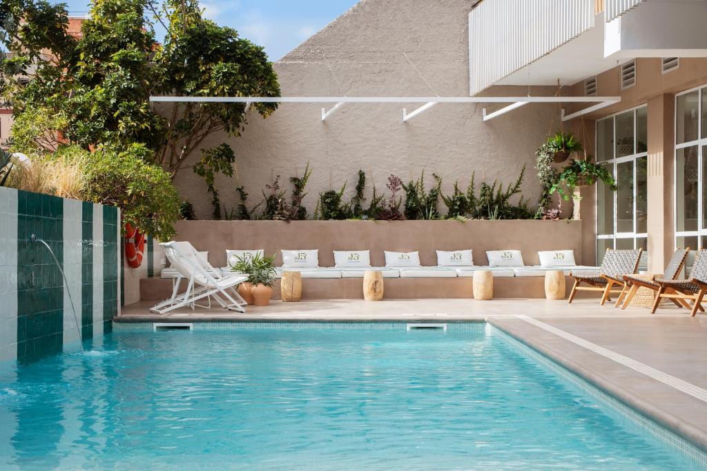 una piscina con sillas blancas junto a un edificio en The 15th Boutique Hotel by Bondia Group, en Lloret de Mar