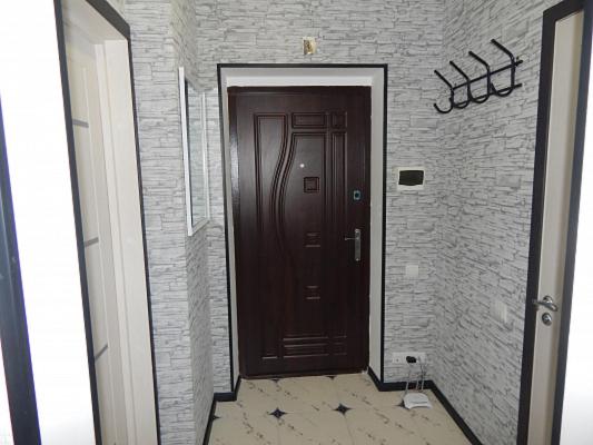 um corredor com uma porta castanha e uma parede de tijolos em Ukrainska Apartment em Irpin