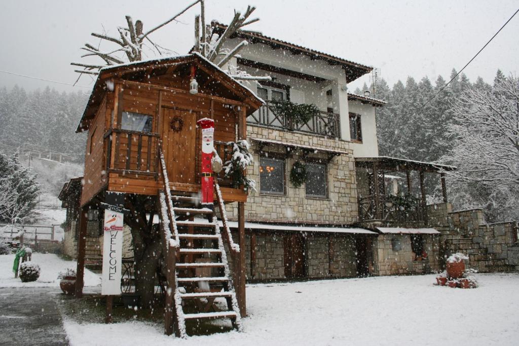 una casa sull'albero nella neve di fronte a una casa di Villa Filokosta a Pertouli (Pertoúlion)