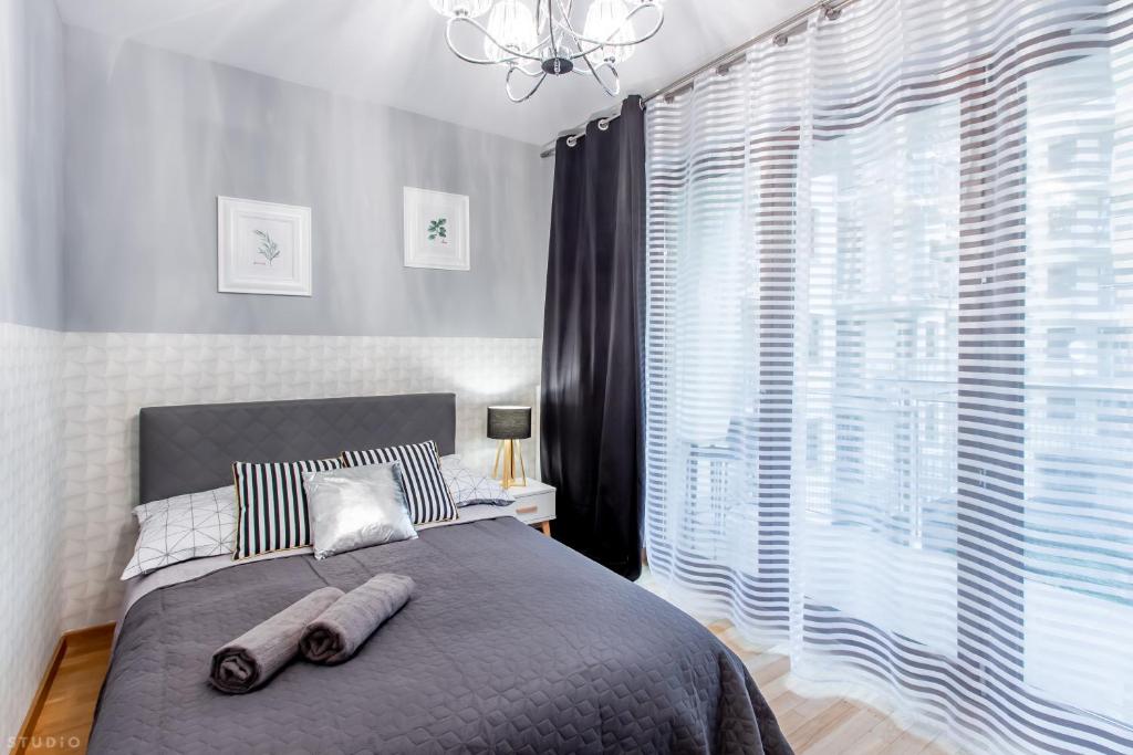 a bedroom with a bed and a large window at ClickTheFlat Sienna Center Apart Rooms in Warsaw