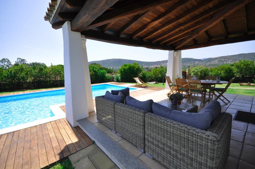 patio con divano e tavolo accanto alla piscina di Capannizza Villas a Budoni