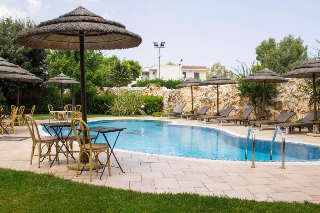 un patio con tavoli, sedie e ombrelloni accanto alla piscina di Semiramide Palace Hotel a Castellana Grotte