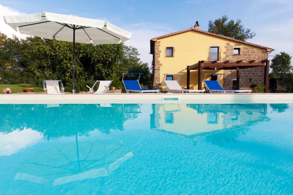 ein Pool mit Stühlen und einem Sonnenschirm und ein Haus in der Unterkunft FicOlivo in Pitigliano