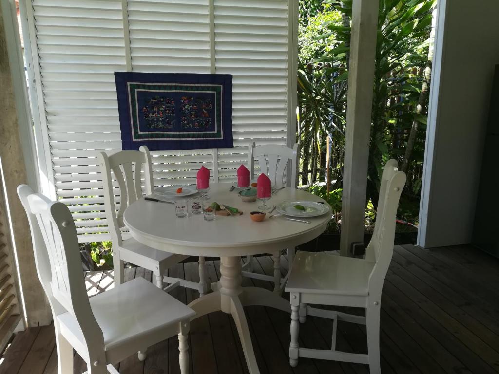 einen weißen Tisch und Stühle auf einer Veranda in der Unterkunft la case dentelle bungalow in Le Diamant