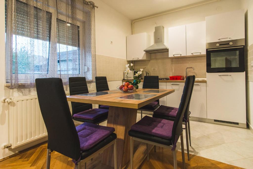 cocina con mesa de madera y sillas moradas en Apartments "Pavić" near Zagreb Airport, en Velika Gorica