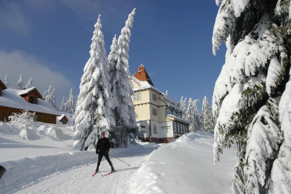 腓特烈罗达Hotel und Berggasthof Spießberghaus的一个人在房子前面的雪中滑雪