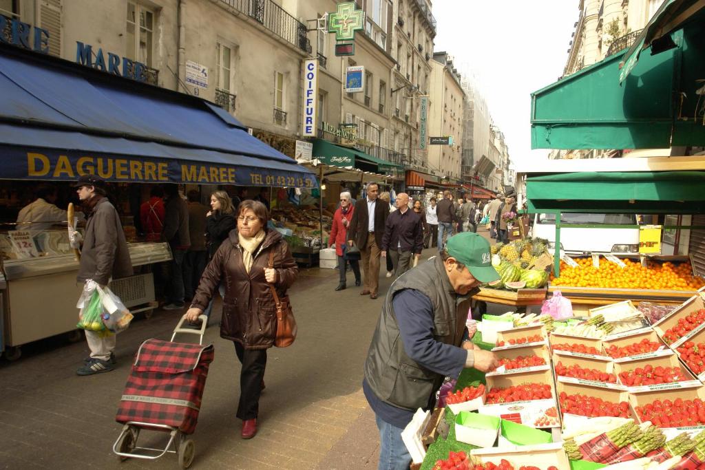 een groep mensen die door een markt wandelen met groenten en fruit bij Montparnasse Daguerre in Parijs