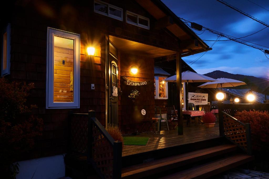 une maison avec une véranda la nuit avec un parasol dans l'établissement Lake village donaludo Pension, à Kitashiobara