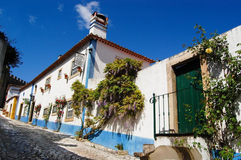 - un bâtiment blanc et bleu avec une porte verte dans l'établissement Casa Do Relogio, à Óbidos