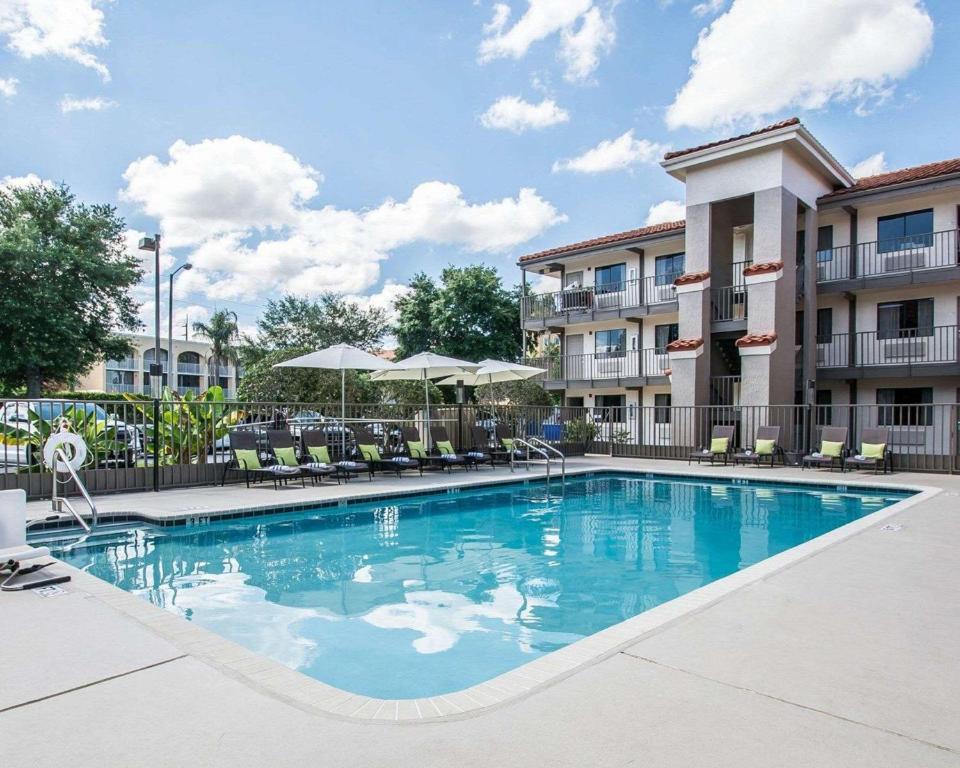 uma piscina com cadeiras e guarda-sóis num hotel em Quality Inn & Suites By the Parks em Orlando