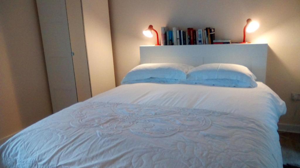 a bedroom with a white bed with two blue pillows at Highfield Cottage in Kirknewton