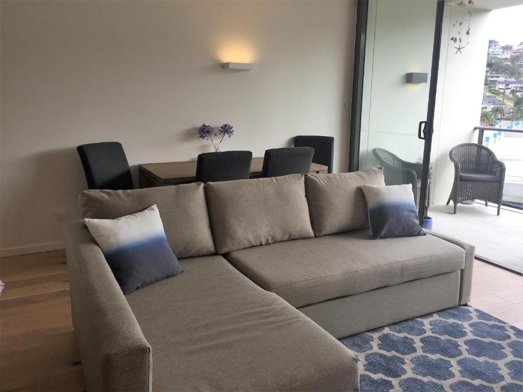 ein Wohnzimmer mit einem Sofa mit Kissen darauf in der Unterkunft Modern & Cozy Unit Just Steps from Terrigal Beach in Terrigal