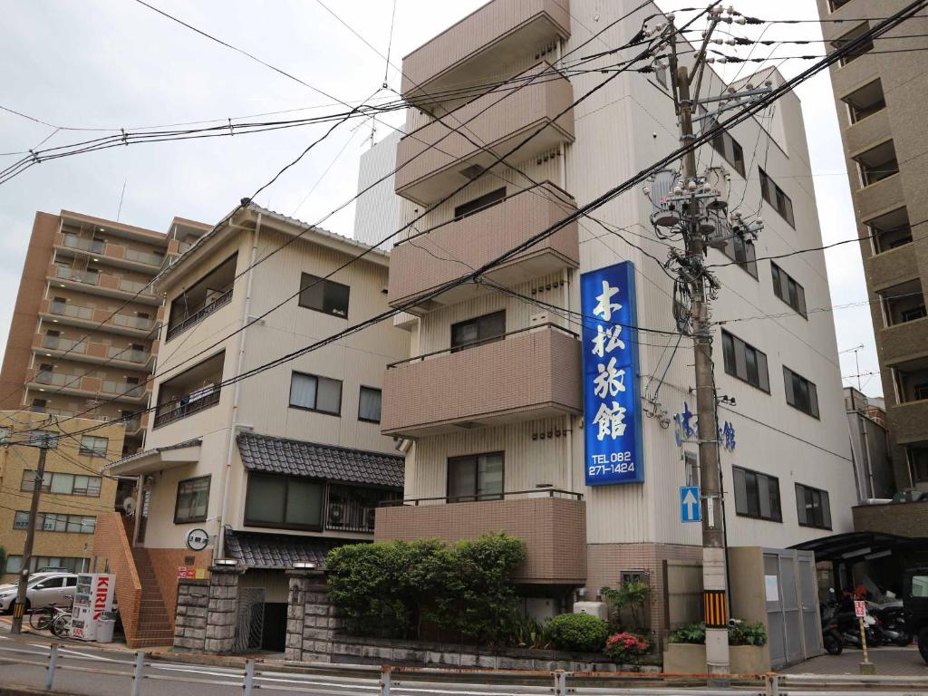 ein Gebäude mit einem blauen Schild davor in der Unterkunft Kimatsu Ryokan in Hiroshima