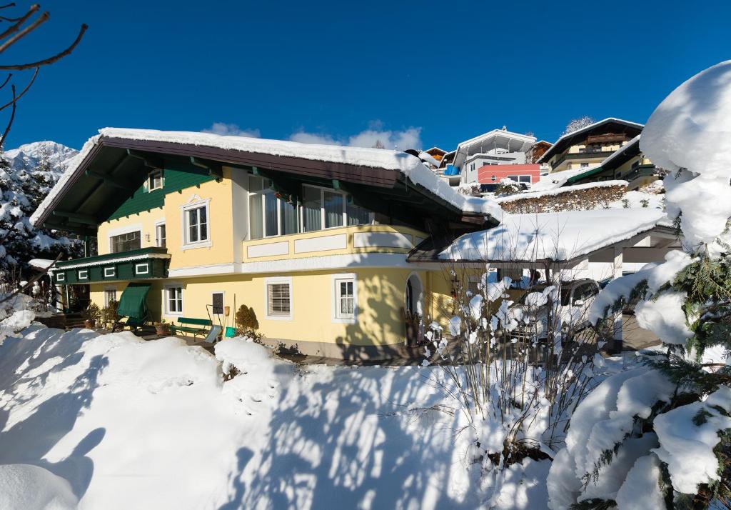 een geel huis in de sneeuw met sneeuw bedekte bomen bij Apartment Lausbuam in Mühlbach am Hochkönig