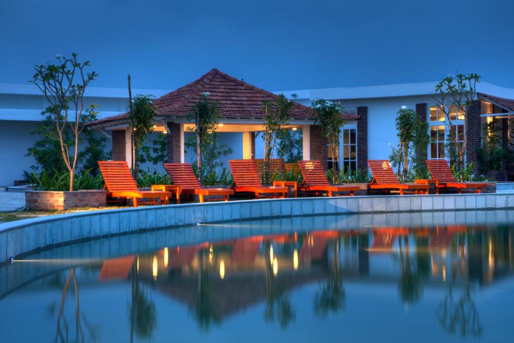 eine Gruppe von Stühlen neben einem Pool in der Unterkunft K RESORT in Puducherry