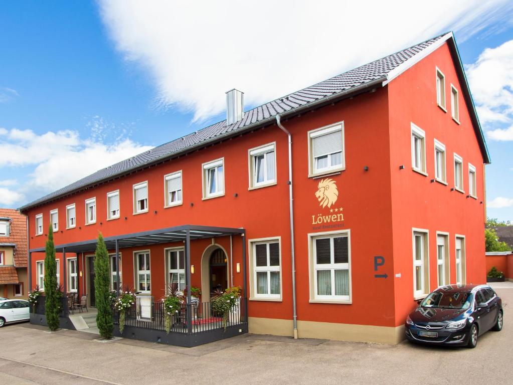 een rood gebouw met een auto ervoor geparkeerd bij Hotel Löwen Garni - B&B in Rust