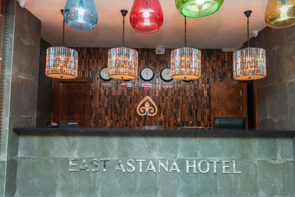 um hotel com luzes chinesas e relógios na parede em East Astana Hotel em Astana