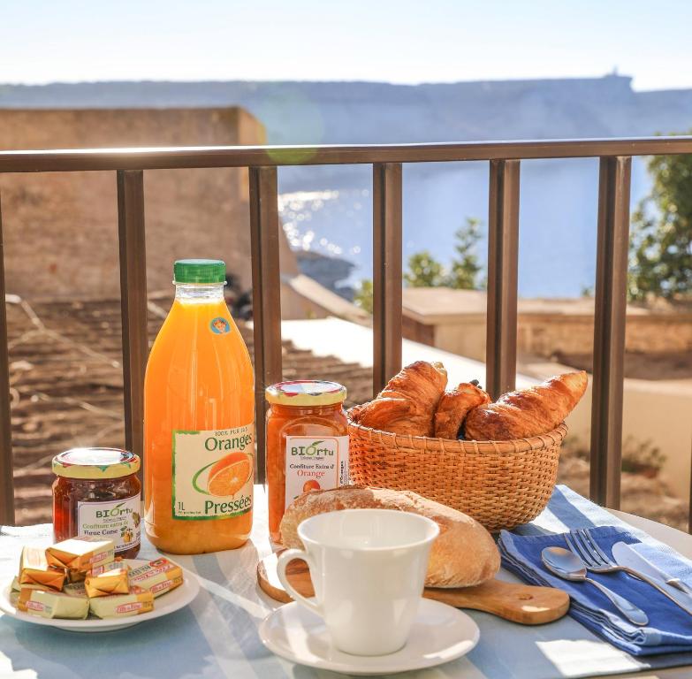 een tafel met een broodmand en een fles jus d'orange bij Faro di Capo Testa in Bonifacio