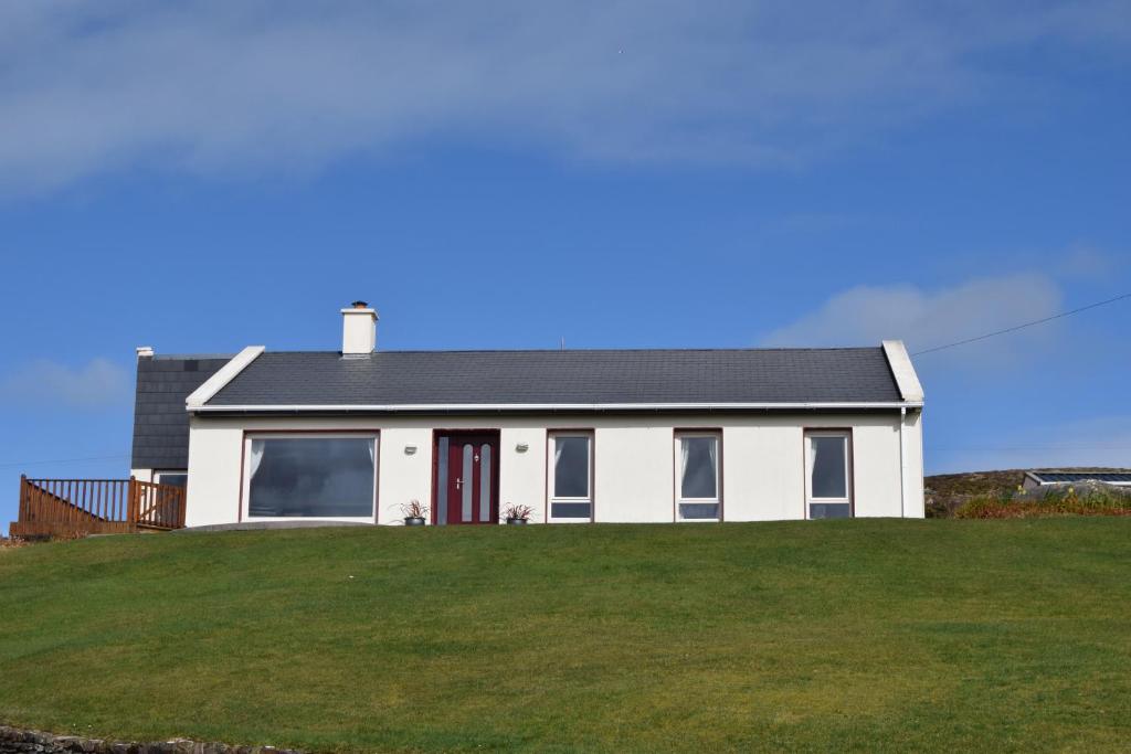 Ard na Carraige, Ventry Holiday Home في دينغل: منزل أبيض على قمة تلة عشبية