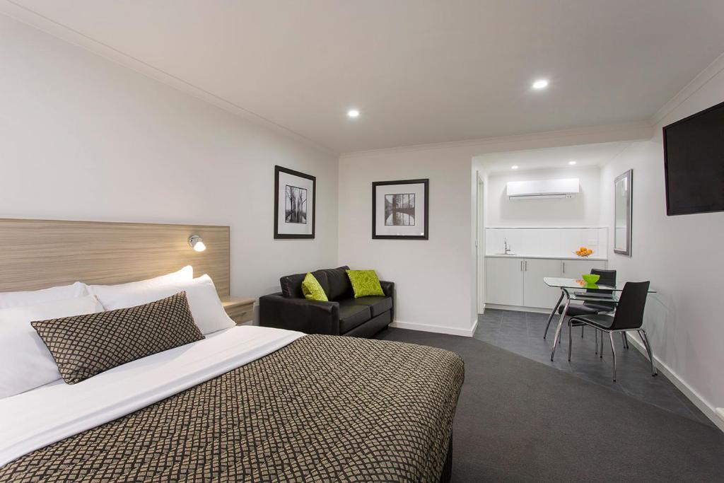 una camera con letto, sedia e scrivania di Hamilton Lonsdale Motel a Hamilton