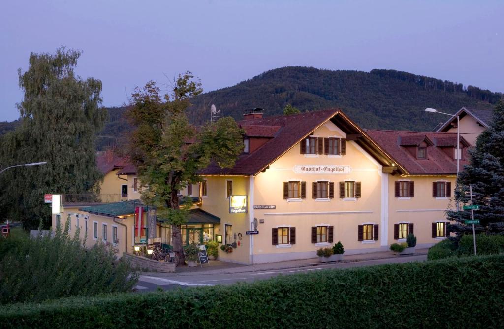 un grand bâtiment blanc avec une montagne en arrière-plan dans l'établissement Gasthof Engelhof, à Gmunden