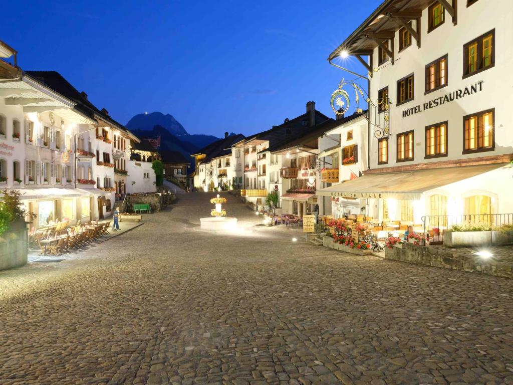 eine Straße in einer Stadt in der Nacht mit Gebäuden in der Unterkunft Hôtel de Ville in Gruyères