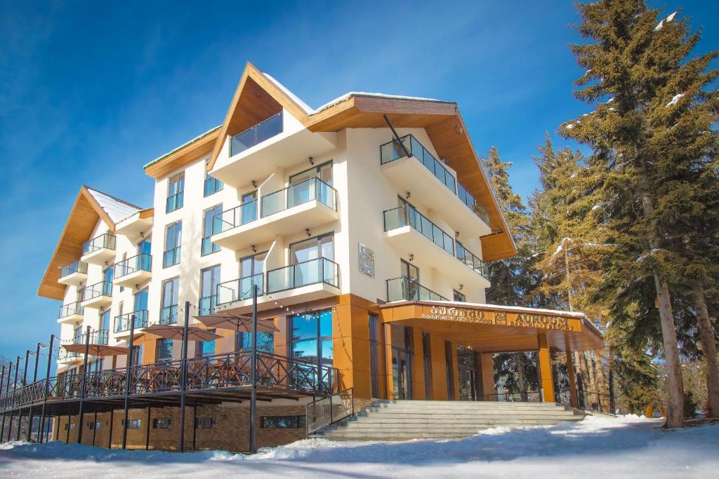 un bâtiment dans la neige avec des arbres devant lui dans l'établissement AuRoom Bakuriani Resort, à Bakuriani