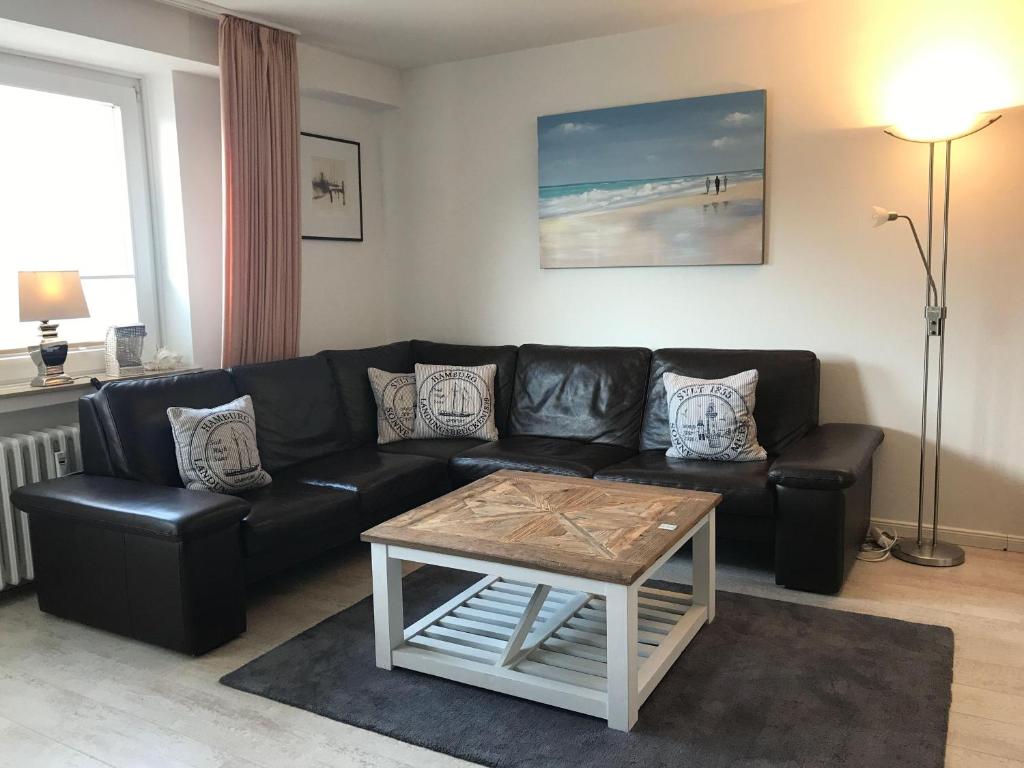 een woonkamer met een zwarte leren bank en een tafel bij Seebrise-Sylt in Westerland