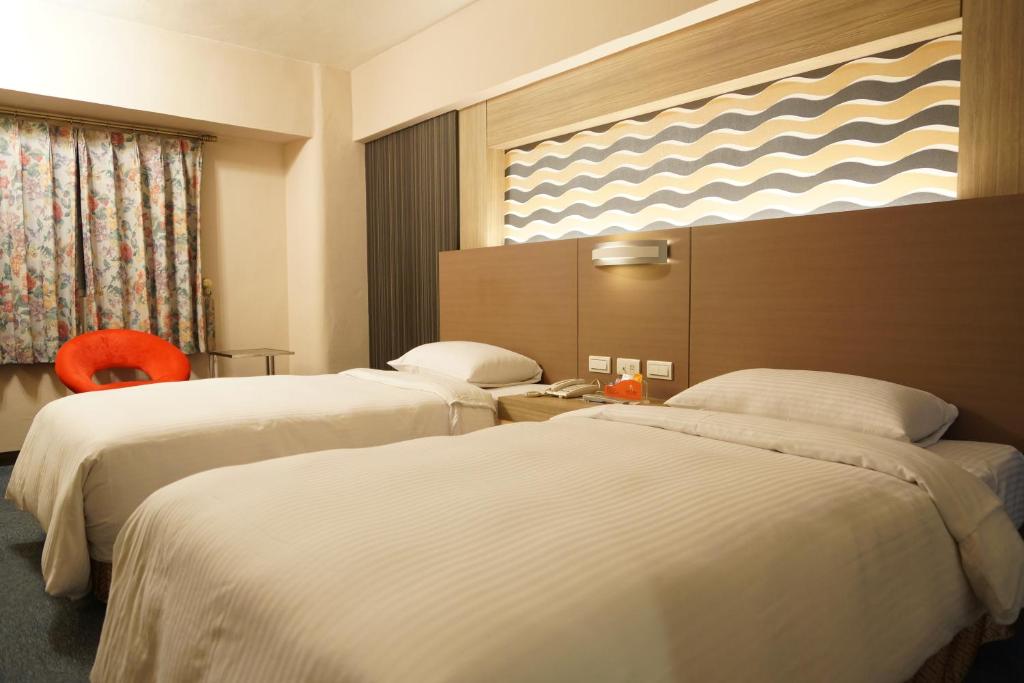 um quarto de hotel com duas camas e uma janela em Ying Dai Hotel em Tainan