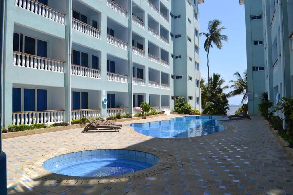 ein Gebäude mit einem Pool vor einem Gebäude in der Unterkunft B12 Cowrie Beach Studio Apartment in Bamburi