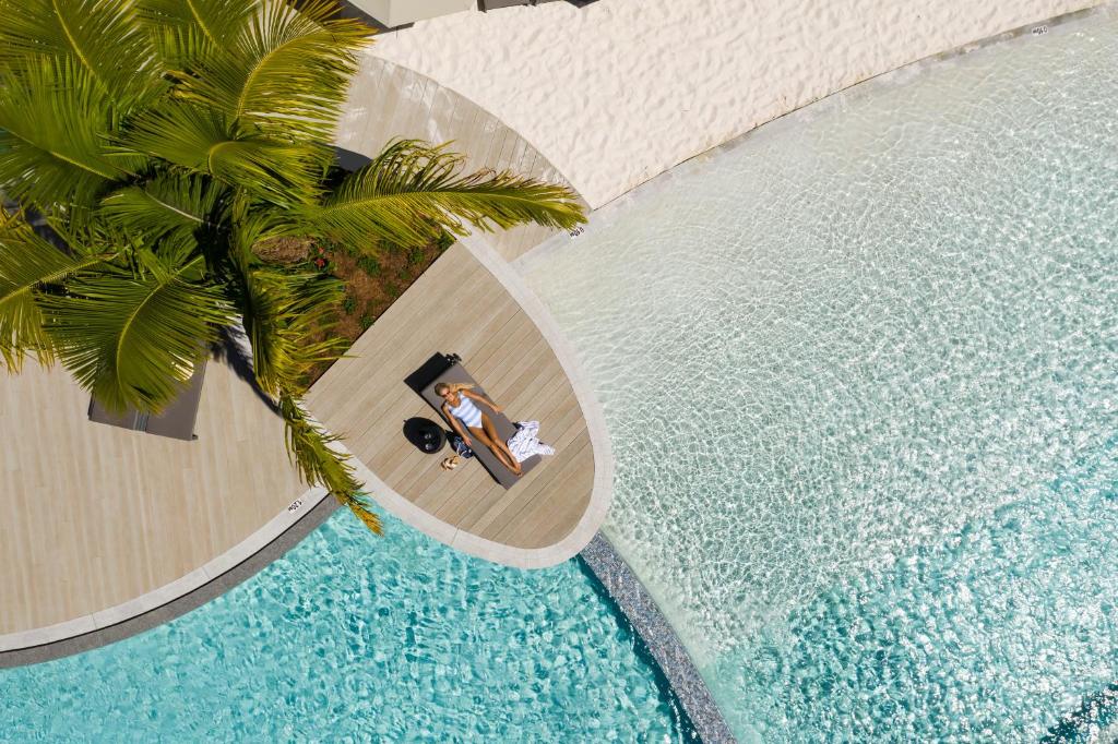 - une vue sur la piscine avec un homme et une femme assis sur une table dans l'établissement Crystalbrook Riley, à Cairns