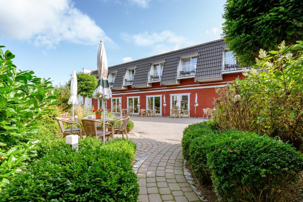 um edifício vermelho com um pátio com uma mesa e cadeiras em Hotel am Schlosspark garni em Husum