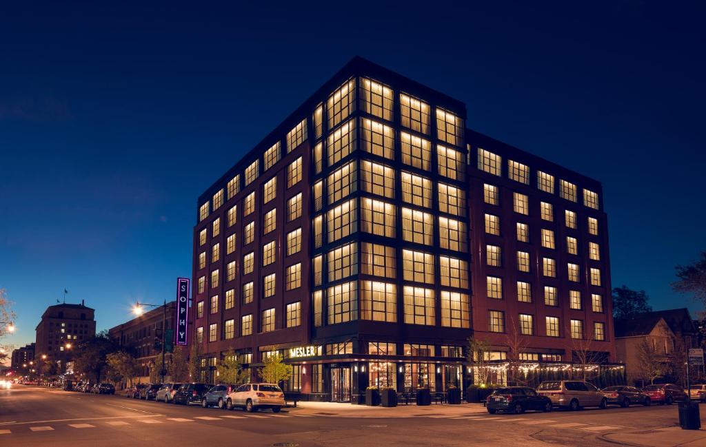 un grand bâtiment avec de nombreuses fenêtres la nuit dans l'établissement Sophy Hyde Park, à Chicago