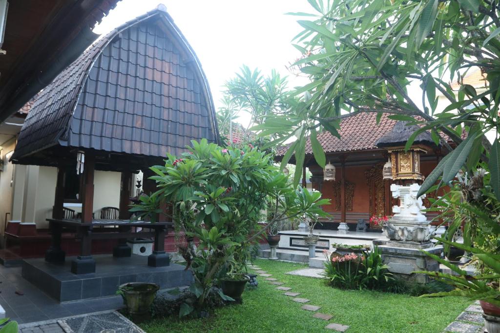 una casa con un patio con árboles y una fuente en Sekar Waru Homestay, en Sanur