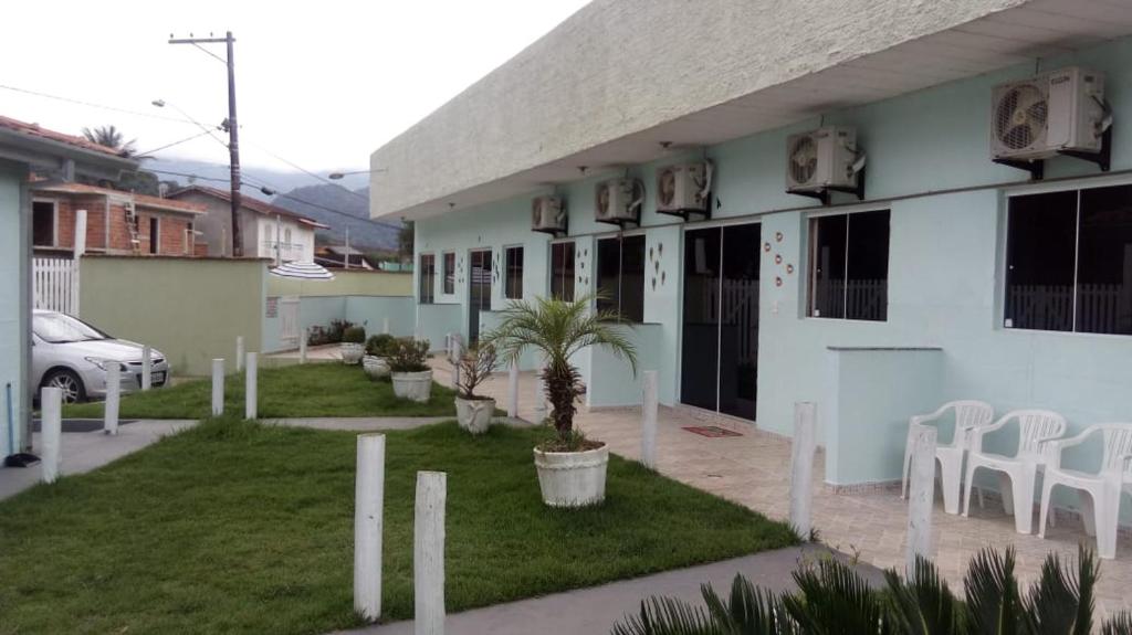 un bâtiment blanc avec des chaises blanches et une cour dans l'établissement Chale Cantinho Albamar, à Ubatuba