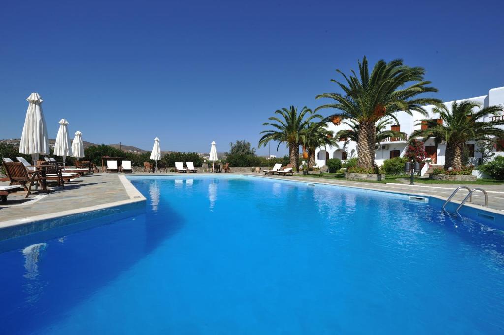 a large blue swimming pool with palm trees and umbrellas at Eri Hotel in Parikia