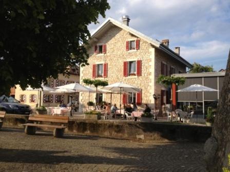 a building with tables and umbrellas in front of it at Au Boeuf Rouge in Crassier