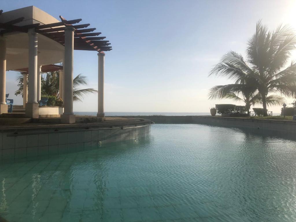 a swimming pool in front of a house with palm trees at Almasi Oceanfront Nyali in Mombasa